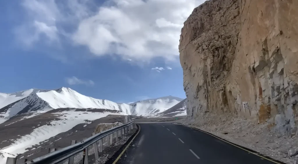 A scenic mountain road winding through snow-covered peaks and rugged cliffs during the Manali to Ladakh road expedition.
