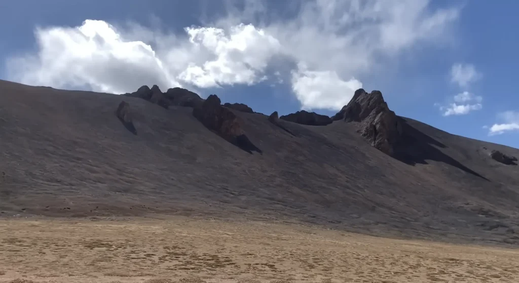 Rugged barren mountain peaks under dramatic clouds along the Manali to Ladakh road expedition route.
