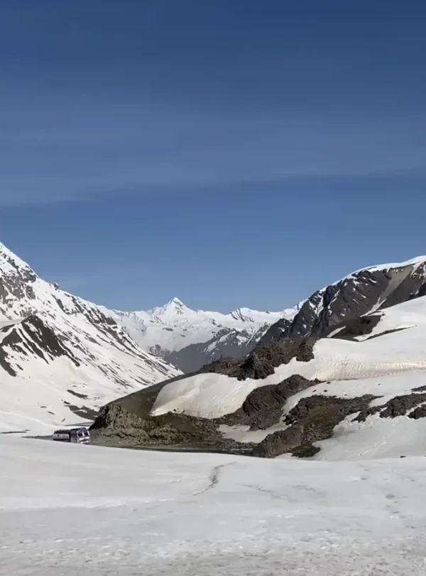 Snow-covered Himalayan mountains and a high-altitude valley under a clear blue sky during the Manali to Ladakh road expedition.